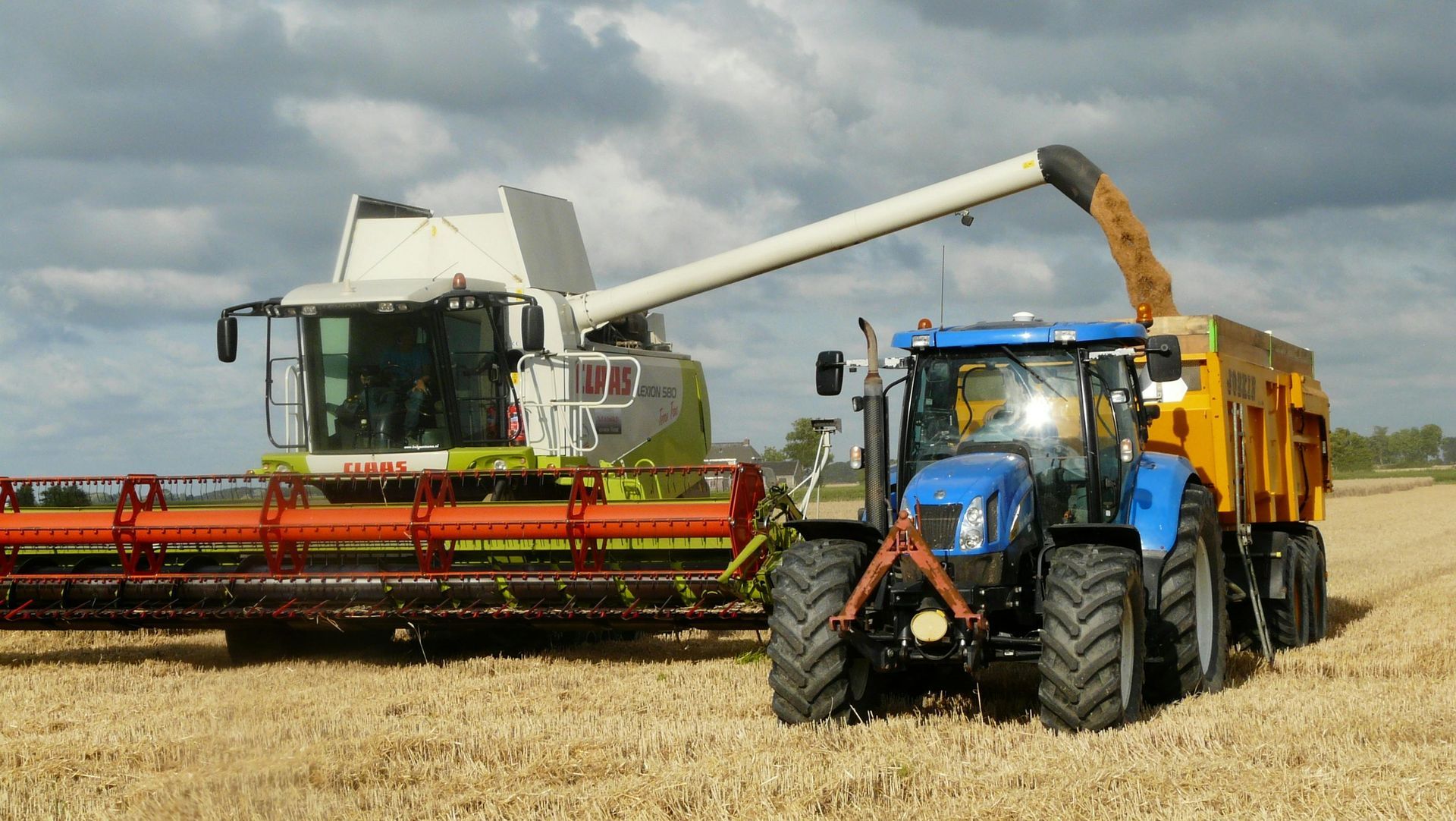A combine harvester and a tractor are working in a field.