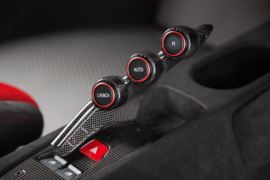A close up of a car 's shifter with red buttons.