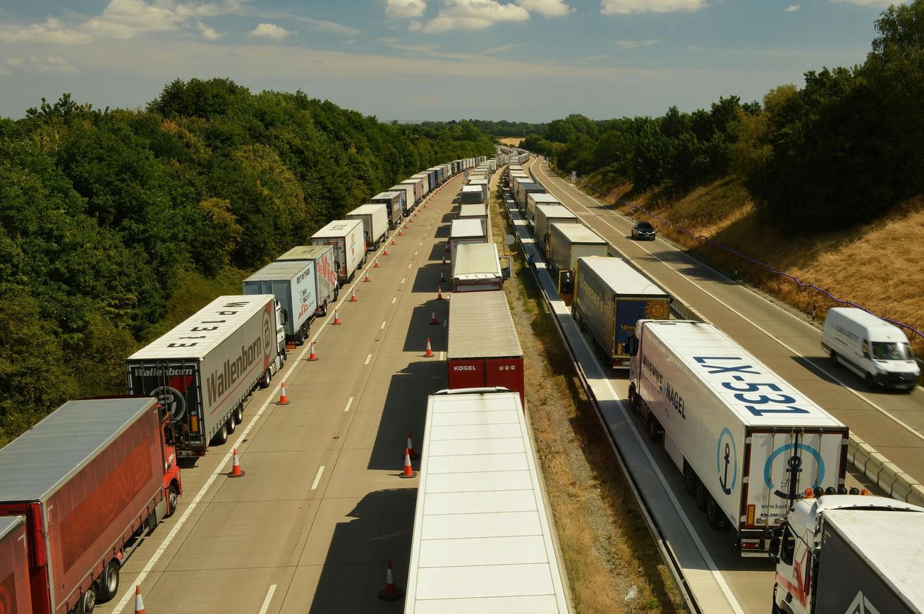 A row of trucks are lined up on a highway and one of the trucks has the number 1651 on it