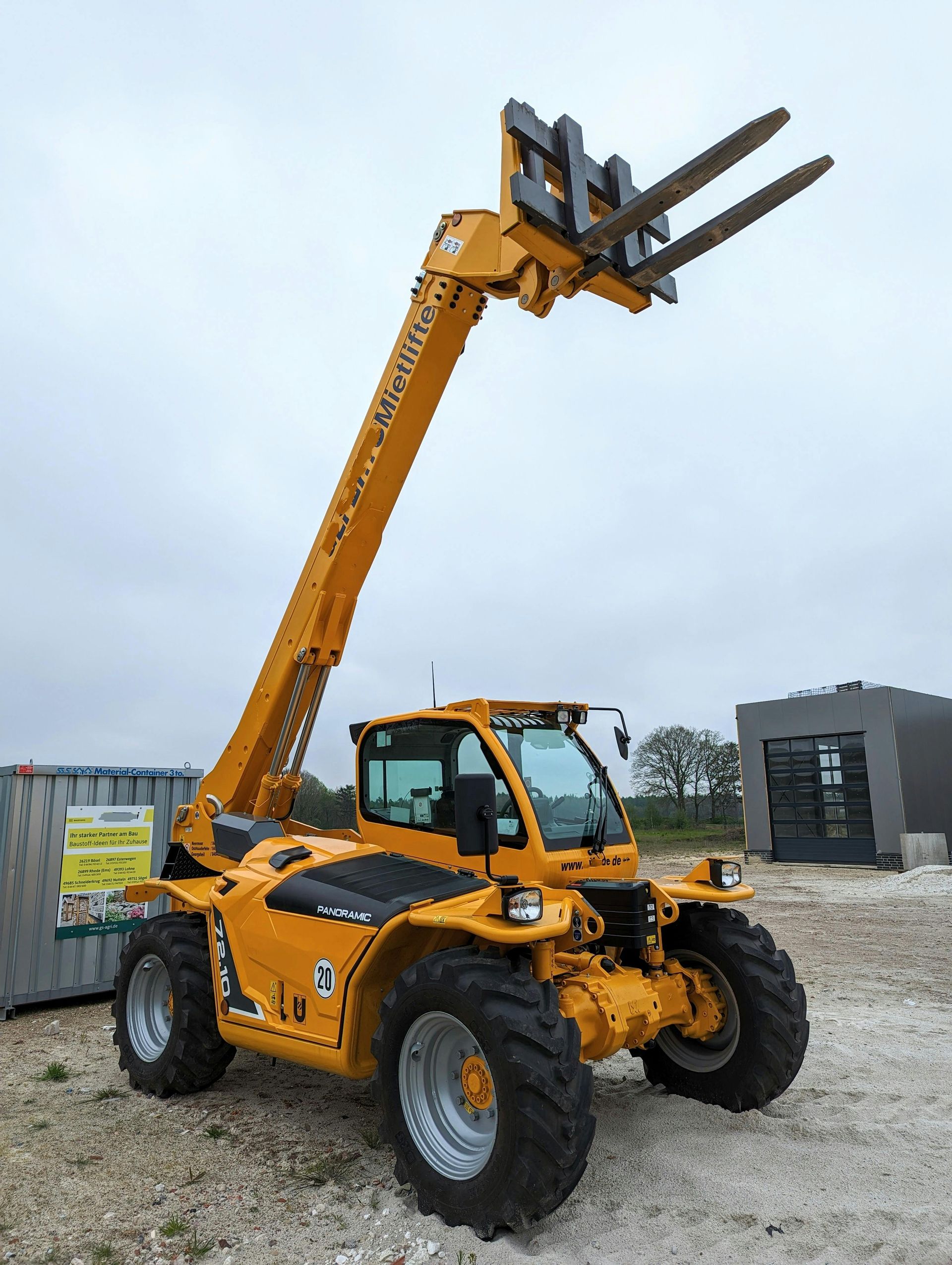 A yellow forklift is parked in a dirt field