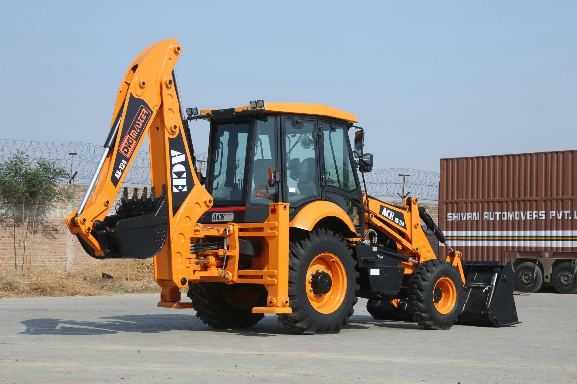 A yellow and black backhoe is parked next to a truck.