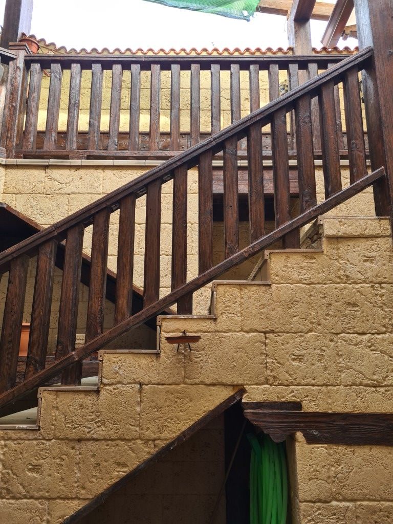 Escalera de piedra con barandilla de madera oscura que conduce a una terraza o balcón.