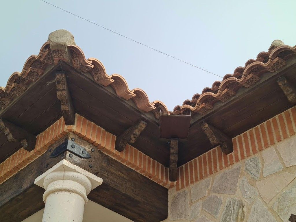 Edificio de piedra con porche de madera marrón y tejado de tejas en un entorno desértico.