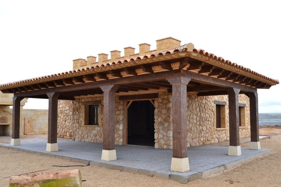 Edificio de piedra con tejado de tejas y vigas de madera en un entorno exterior seco.