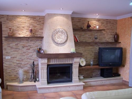 Sala de estar con chimenea de piedra, estanterías empotradas y un televisor en el lado derecho.