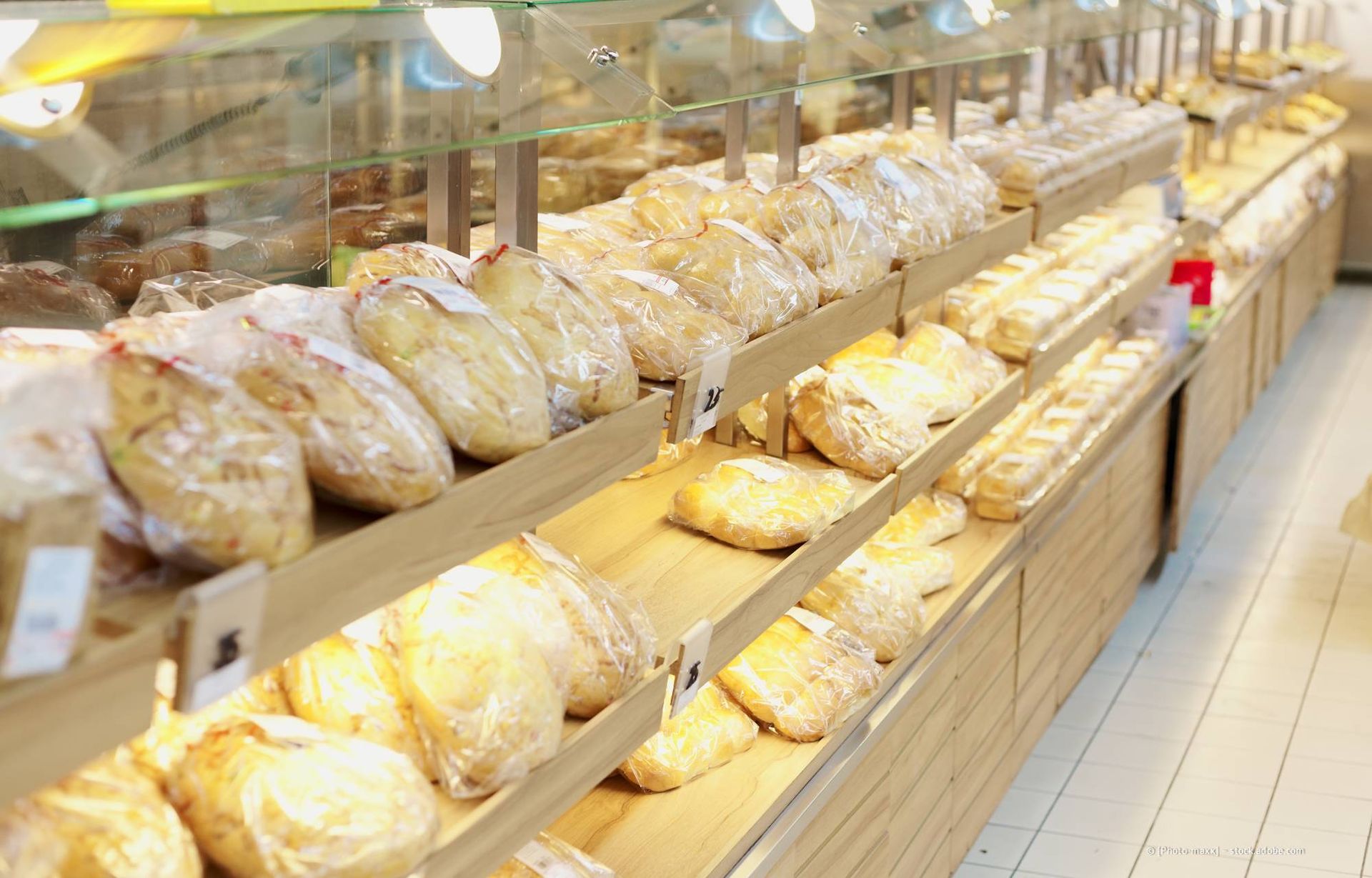 Bäckerei-Auslage mit verschiedenen Brotsorten; Holzregale und warme Beleuchtung.