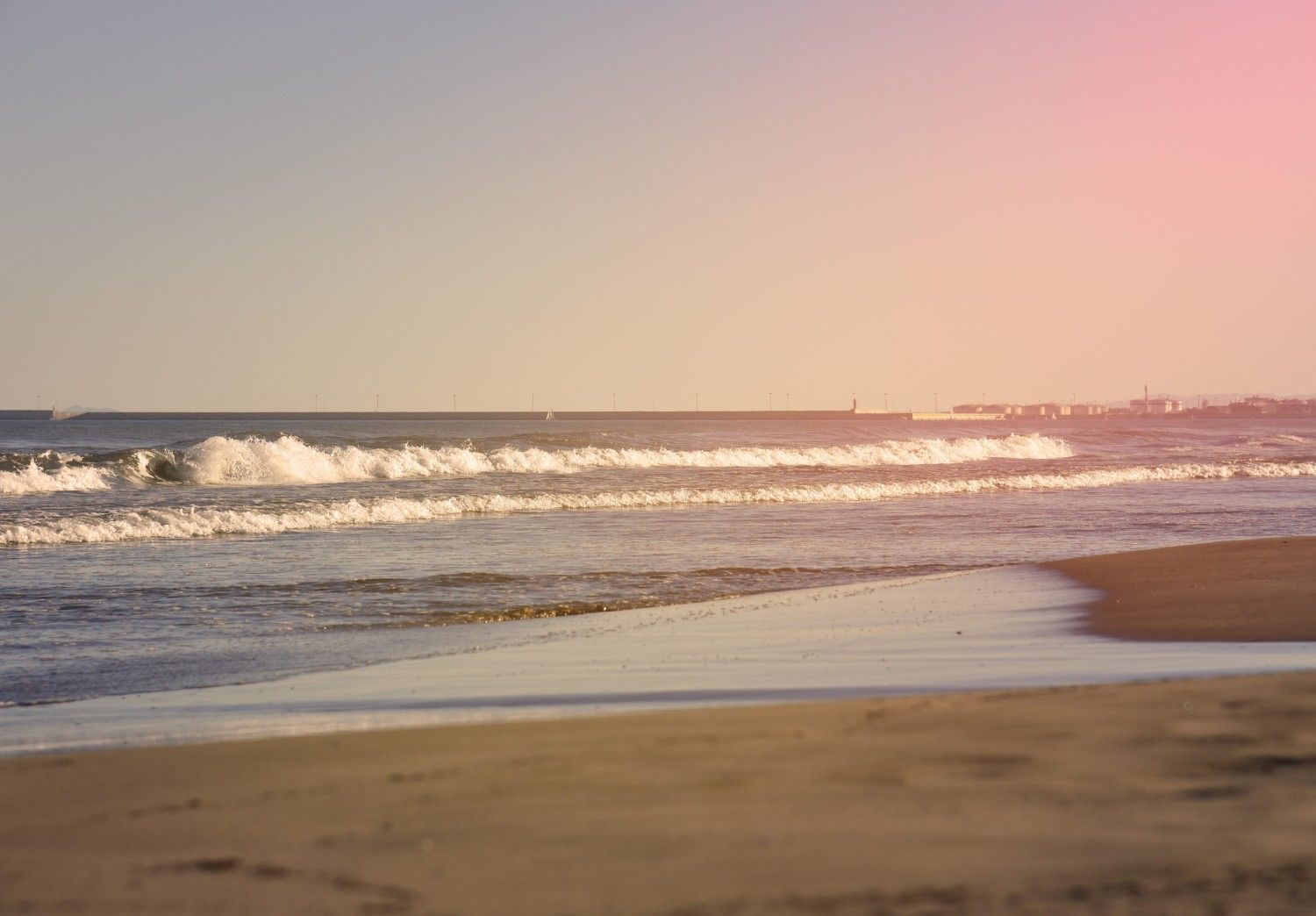 Atardecer sobre una playa tranquila con olas suaves y cielo rosado
