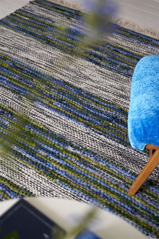 Ein blauer Stuhl steht auf einem blau-grünen Teppich.