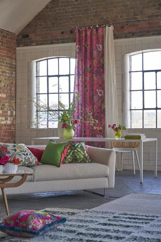 Ein Wohnzimmer mit einer weißen Couch und rosa Vorhängen