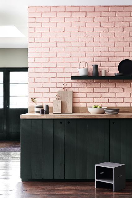Eine Küche mit einer rosa Ziegelwand und schwarzen Schränken