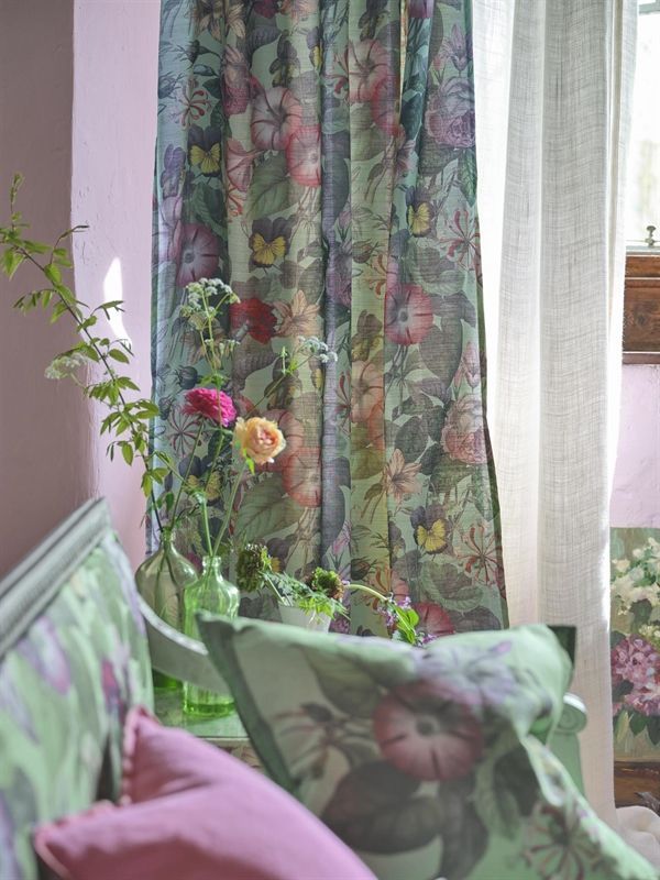 Ein Zimmer mit einer Couch und Kissen und Blumen in einer Vase