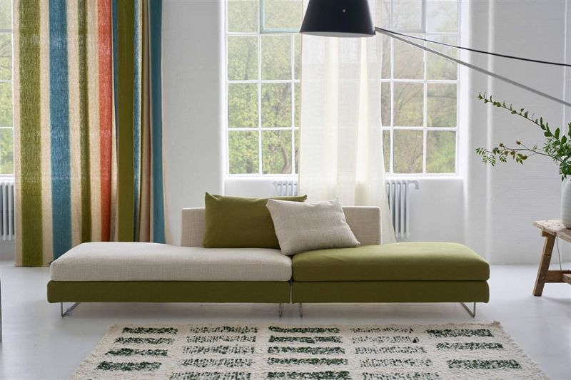 Ein Wohnzimmer mit einer grün-weißen Couch und gestreiften Vorhängen