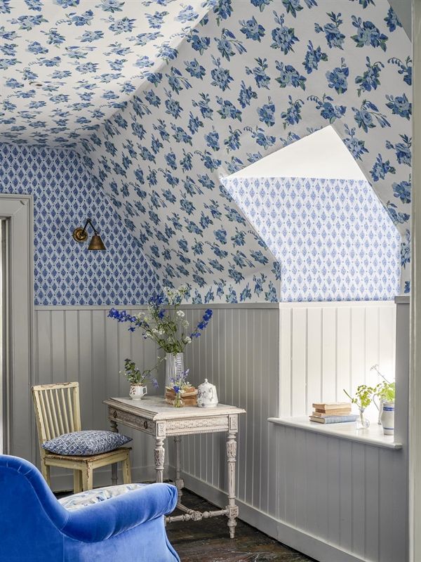 Ein Zimmer mit blau-weißer Blumentapete an der Decke