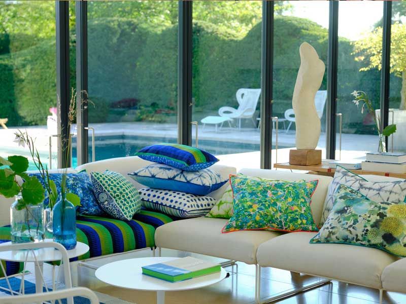 Ein Wohnzimmer mit einer Couch und Kissen und einem Pool im Hintergrund