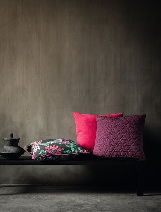 Eine Bank mit drei Kissen und einer Vase darauf