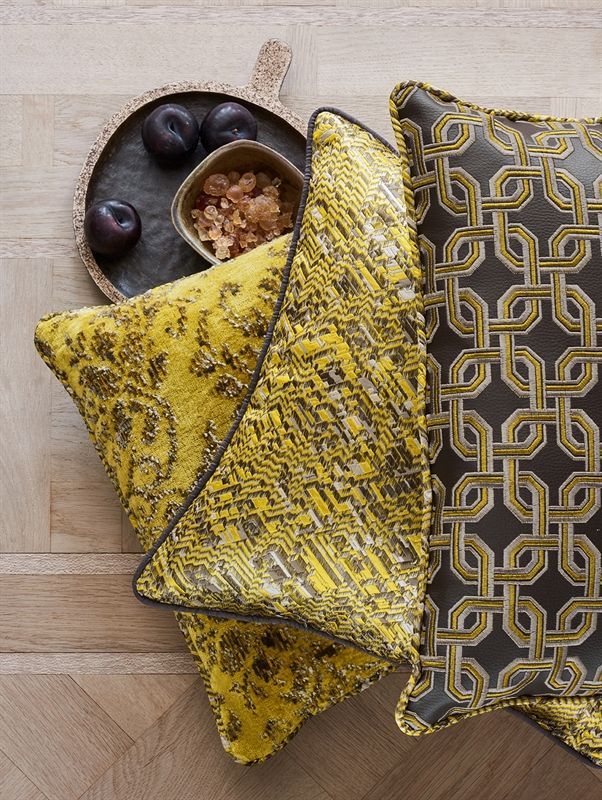 Ein Tablett mit Pflaumen steht auf einem Holztisch neben zwei gelben Kissen