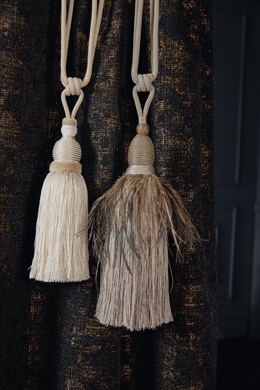Zwei Quasten hängen an einem schwarz-goldenen Vorhang