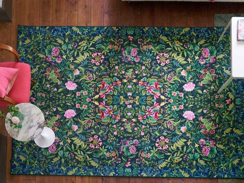 Ein Teppich mit rosa Blumen und grünen Blättern darauf