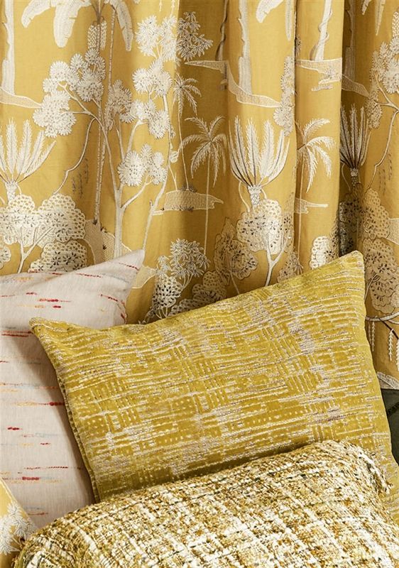 Ein Bett mit gelben Vorhängen und Kissen darauf