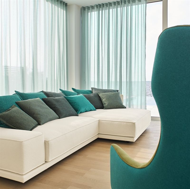 Ein Wohnzimmer mit einer weißen Sofagarnitur und einem blauen Sessel