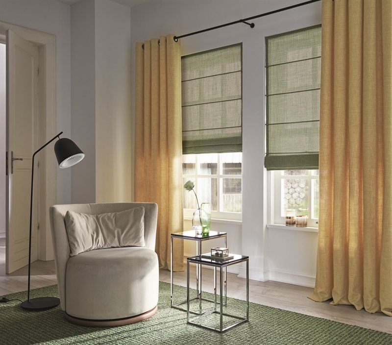 Ein Wohnzimmer mit Stuhl, Tisch, Lampe und Vorhängen