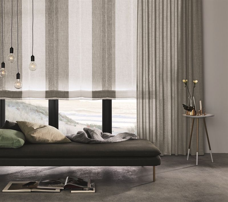 Ein Wohnzimmer mit einer Couch und einem Fenster mit Vorhängen