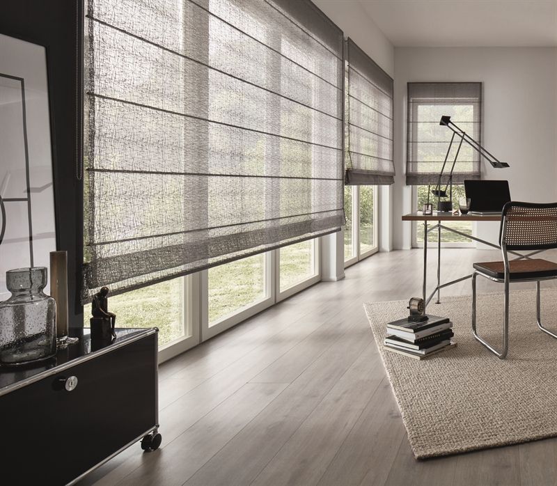 Ein Wohnzimmer mit vielen Fenstern und Rollos