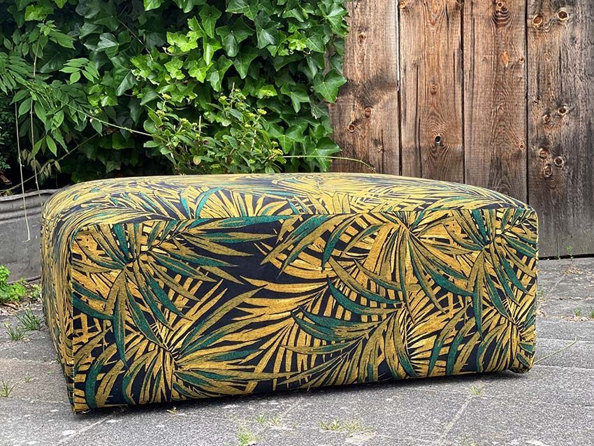 Vor einem Holzzaun steht ein gelb-grüner Ottomane.