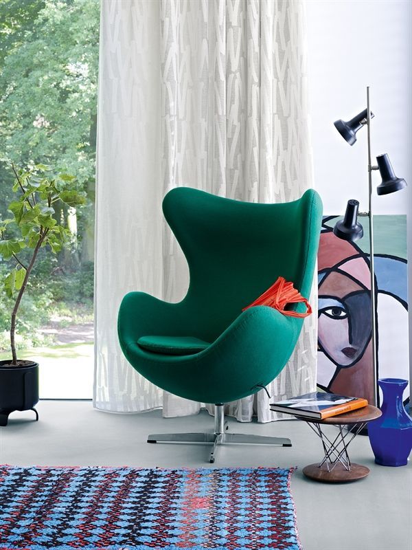 Ein grüner Eierstuhl steht vor einem Fenster