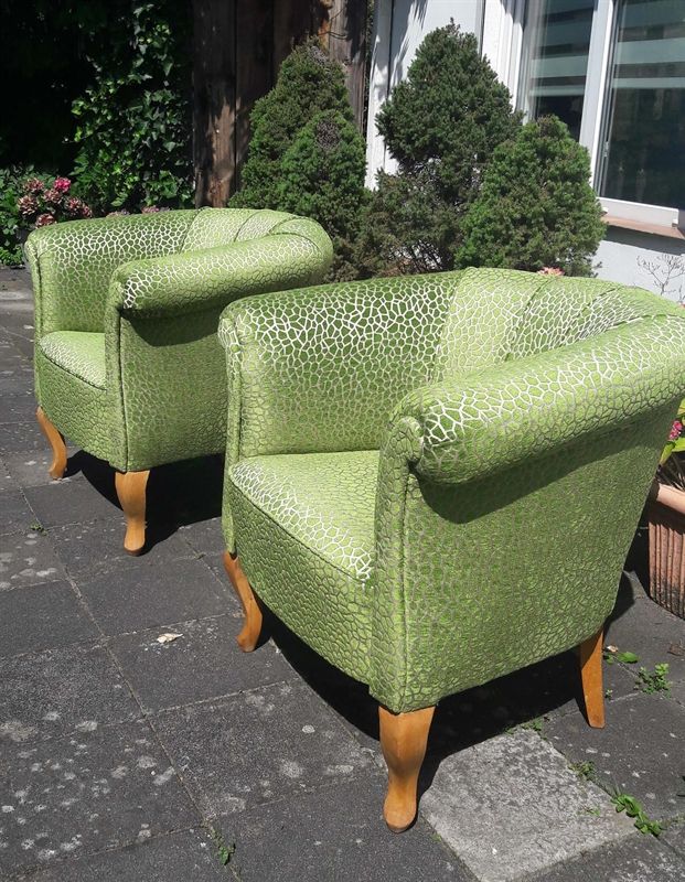 Zwei grüne Stühle stehen auf einem Bürgersteig vor einem Haus