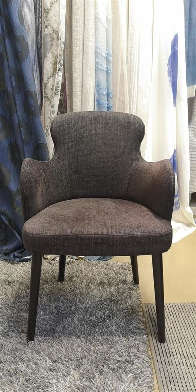 Ein Stuhl steht auf einem Teppich vor Vorhängen.