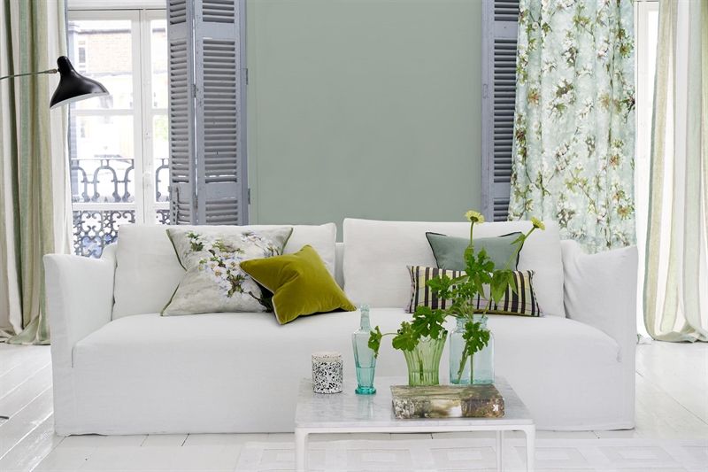 Ein Wohnzimmer mit einer weißen Couch und grünen Kissen