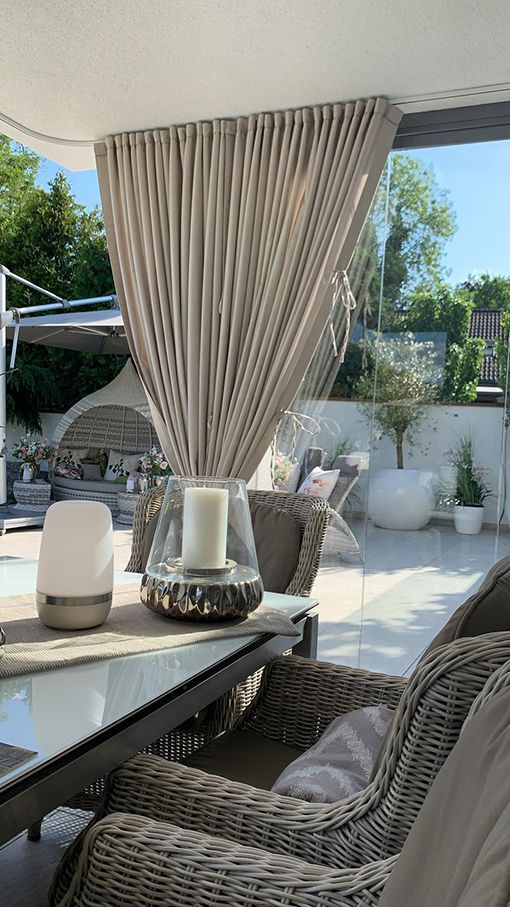 Eine Terrasse mit Korbstühlen und einem Tisch mit einer Kerze darauf.