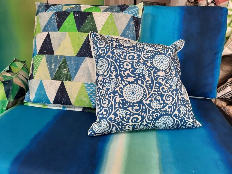 Blaue und grüne Kissen auf einem blau-grün gestreiften Sofa