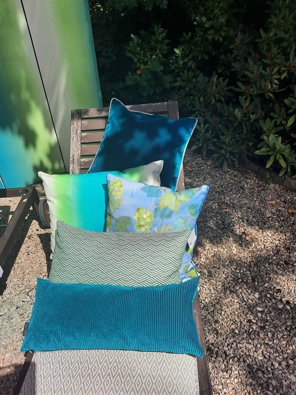 Eine Reihe blauer und grüner Kissen auf einem Stuhl