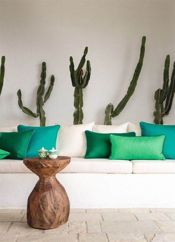 Eine weiße Couch mit grünen Kissen und einem Holztisch