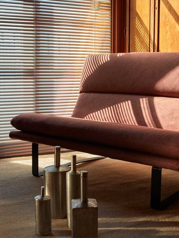 Eine Couch steht vor einem Fenster mit Jalousien