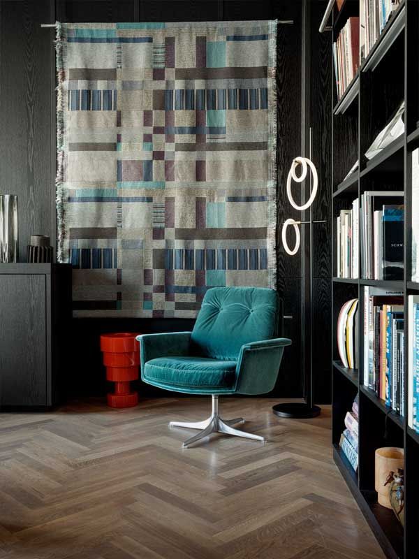 Ein Wohnzimmer mit einem blauen Stuhl und einer Steppdecke an der Wand