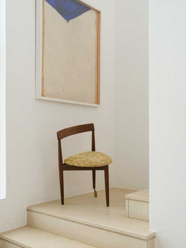 Ein Stuhl steht auf einer Treppe neben einem Gemälde an der Wand