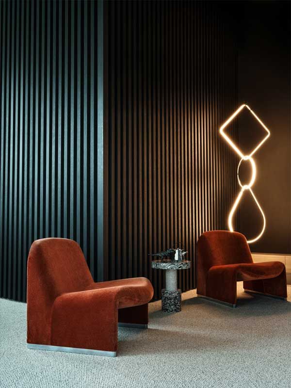 Zwei rote Stühle stehen neben einem Tisch in einem dunklen Raum.