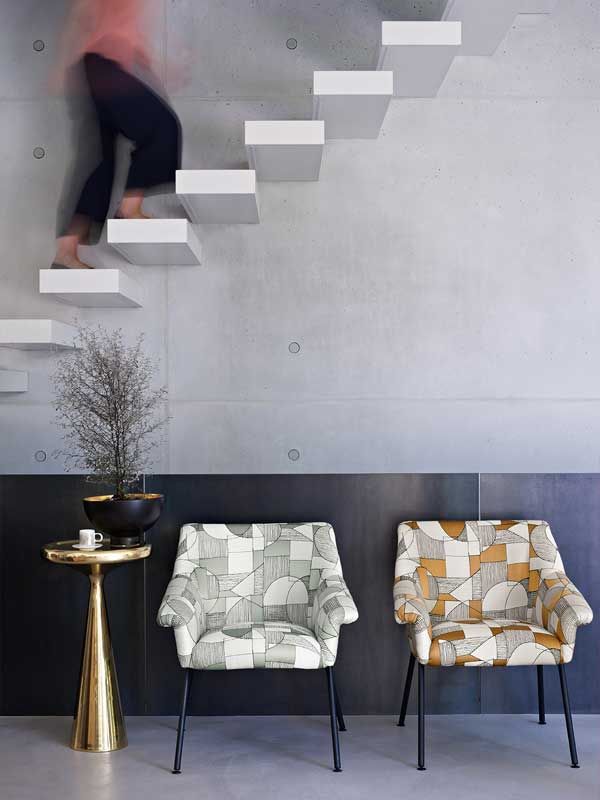 Eine Frau geht neben drei Stühlen eine Treppe hinauf