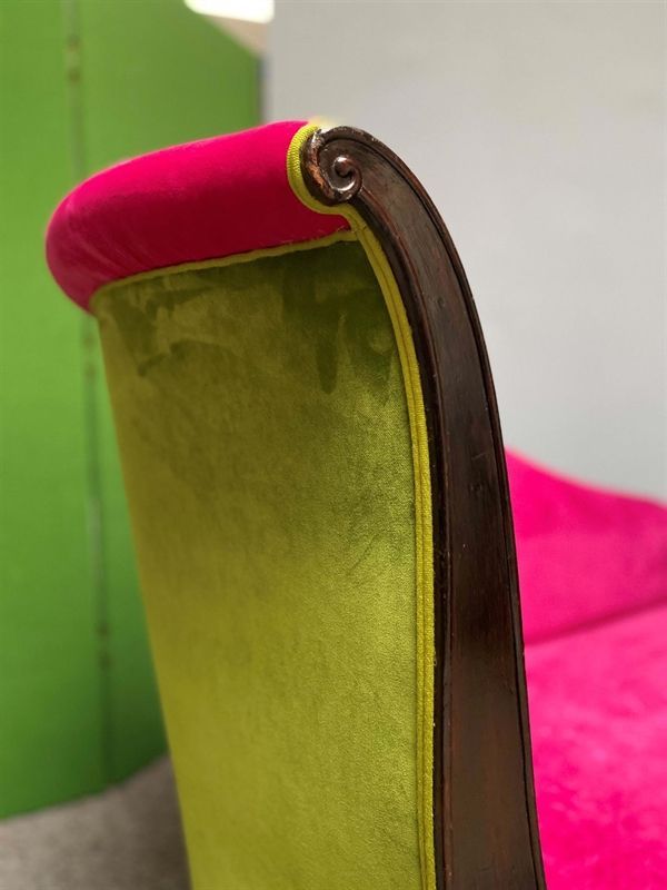 Ein grün-rosa Stuhl mit einer Armlehne aus Holz