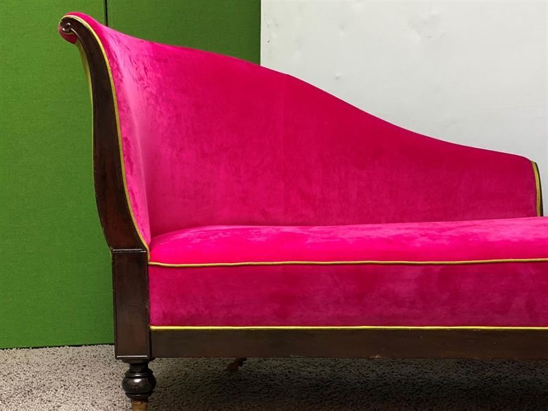 Eine rosa Chaiselongue mit einer grünen Wand im Hintergrund