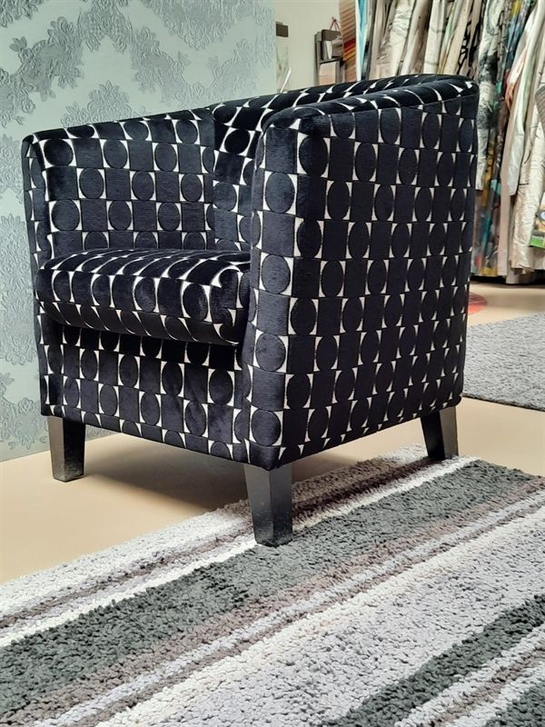 Ein schwarzer Stuhl mit weißen Kreuzen darauf steht auf einem gestreiften Teppich