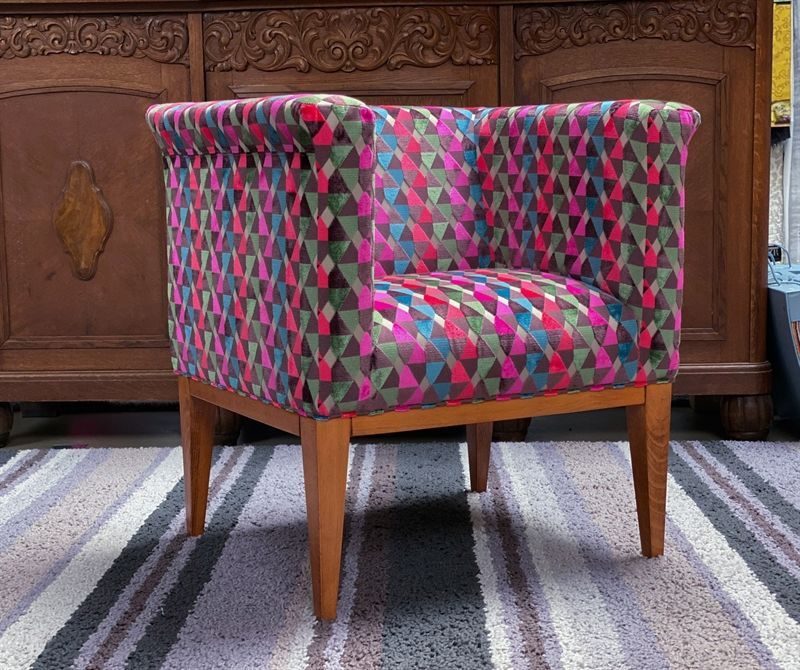 Ein bunter Stuhl steht auf einem gestreiften Teppich