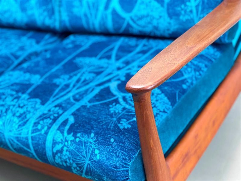 Eine Nahaufnahme eines blauen Sofas mit hölzernen Armlehnen.