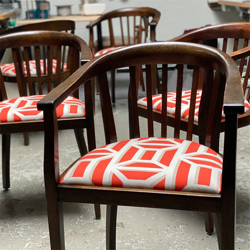 Eine Reihe Holzstühle mit roten und weißen Kissen