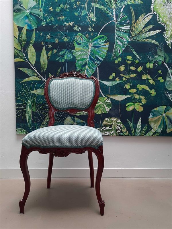 Ein Stuhl vor einem Gemälde mit Blättern