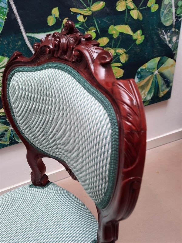 Ein Stuhl vor einem Gemälde mit Blättern darauf