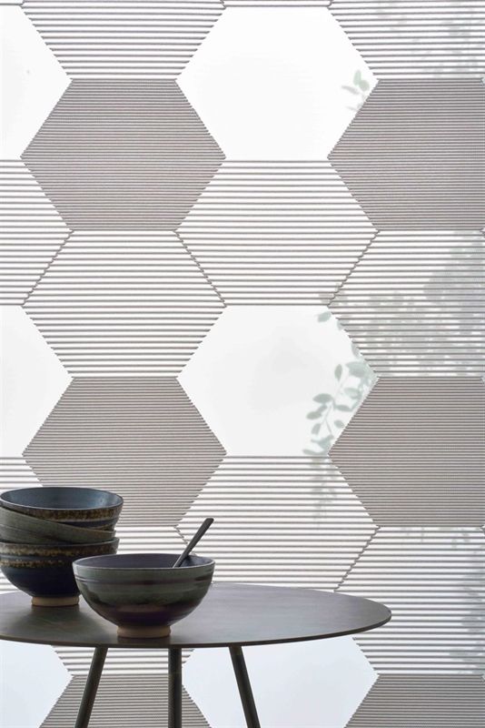 Ein Tisch mit zwei Schüsseln darauf vor einer Wand mit einem geometrischen Muster.